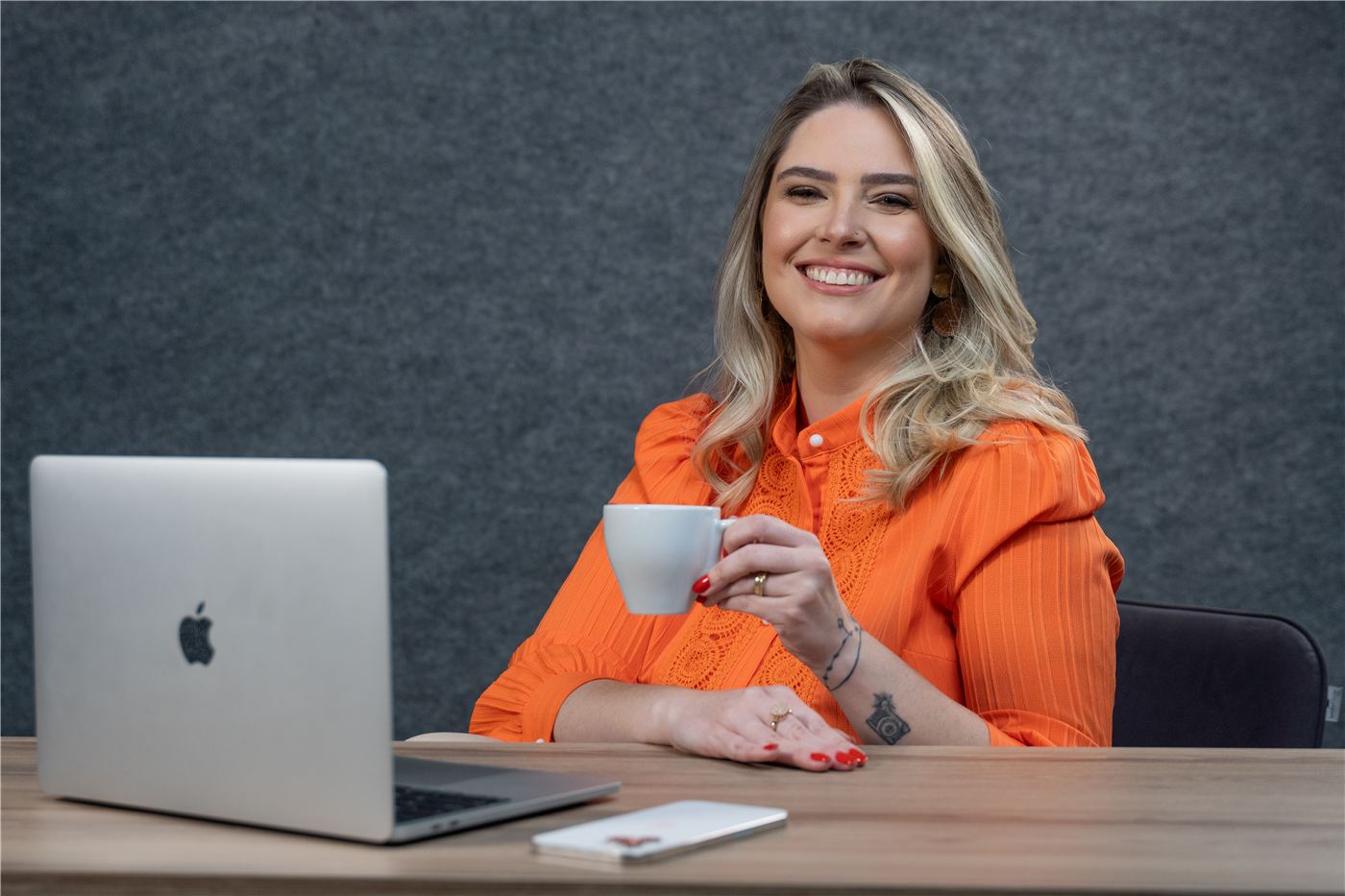 Raphaela Spellmeier sorrindo em frente ao notebook, com uma xícara de café