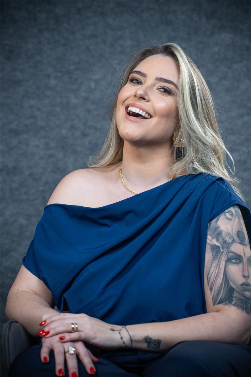 Raphaela Spellmeier sentada, de blusa azul, rindo