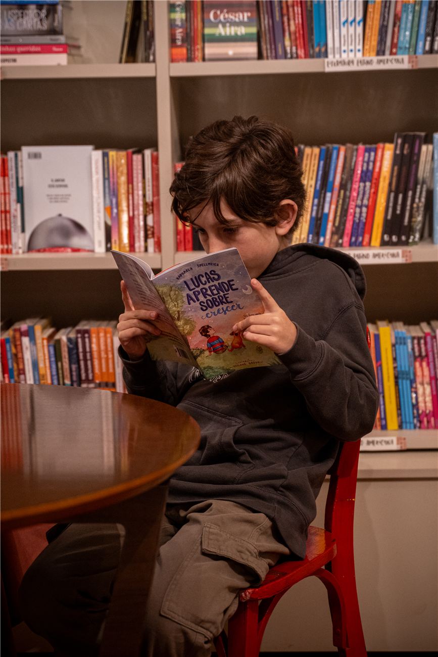 Menino lendo o livro Lucas aprende sobre crescer numa livraria