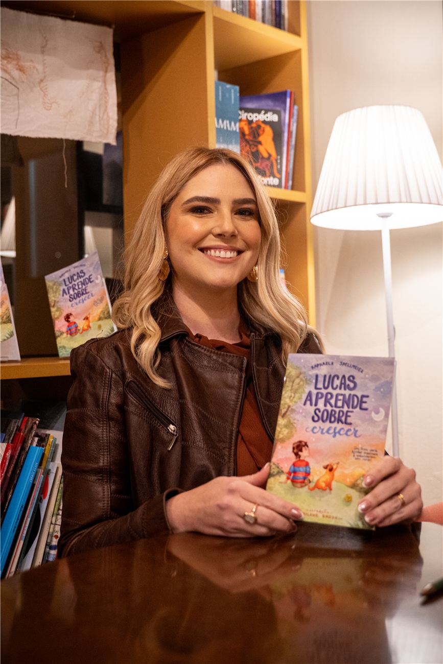 Raphaela Spellmeier sorrindo e segurando o livro Lucas aprende sobre crescer
